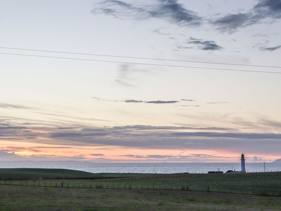 A lighthouse by the ocean during sunset at Corsewall Castle Farm Lodges in Kirkcolm