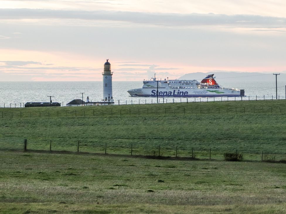 A lighthouse near a ferry on the sea at Corsewall Castle Farm Lodges Kirkcolm