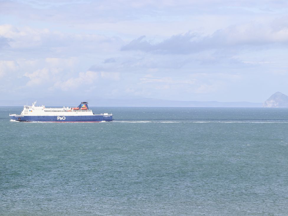 A ferry sailing in the ocean near an island at Corsewall Castle Farm Lodges Kirkcolm