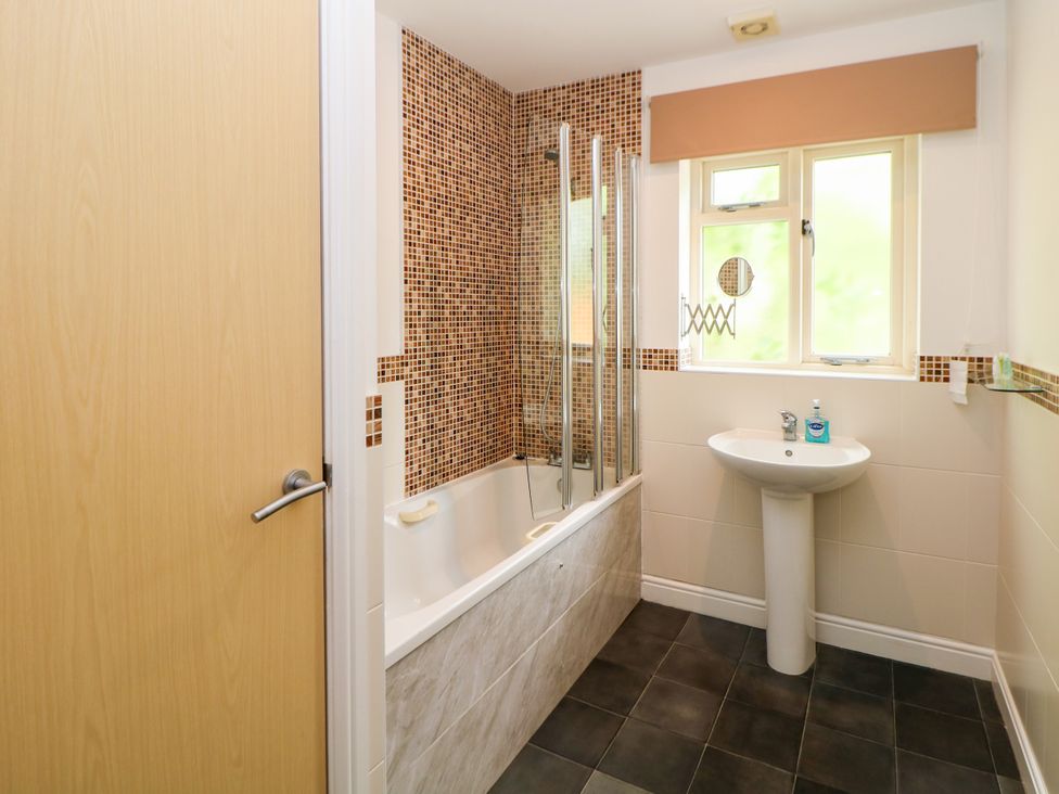 A bathroom with a bathtub, sink, and shower at Wensley in Matlock