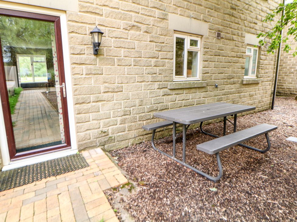 A garden with a table and benches next to a door at Wensley in Matlock