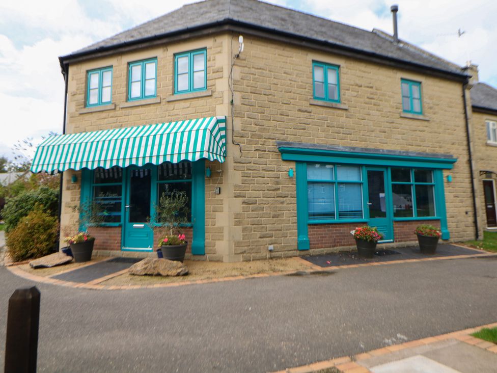 A building with a striped awning and planters at Wensley in Matlock