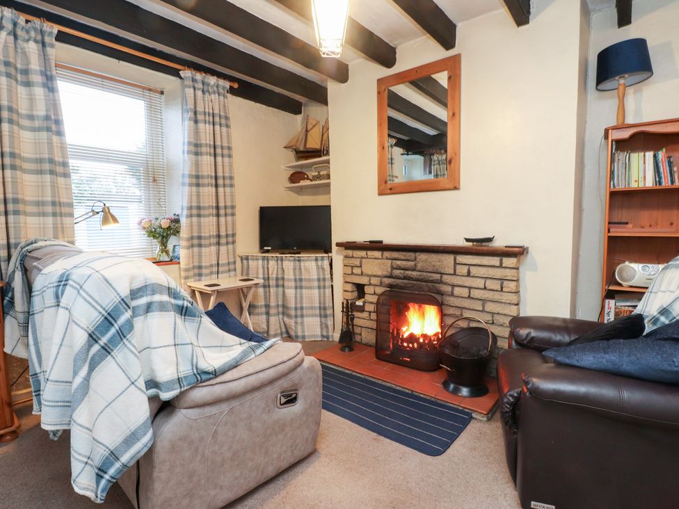 A living room with a fireplace and sofa at Merlin in Llithfaen near Nefyn
