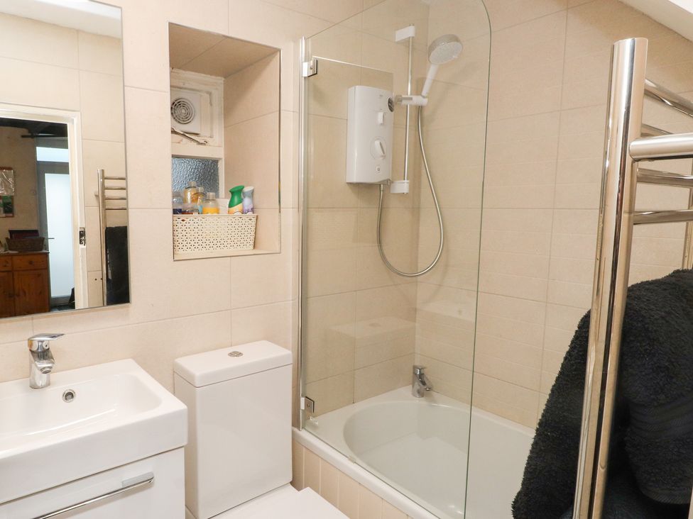 A bathroom with a sink, toilet, and shower at Merlin in Llithfaen near Nefyn