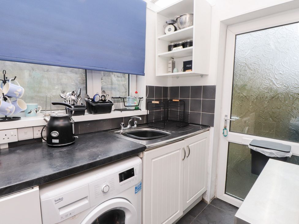 A kitchen with a washing machine and sink at Merlin in Llithfaen near Nefyn