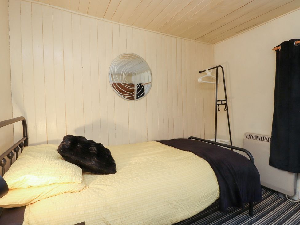 A bedroom with a bed and mirror at Merlin in Llithfaen near Nefyn