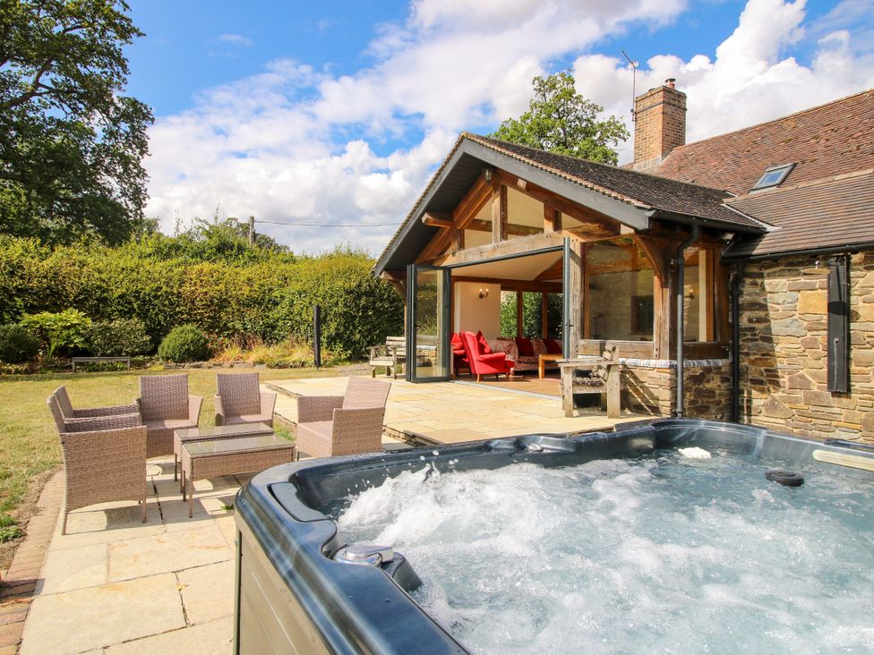 A garden with a hot tub and seating area at The Old Farmhouse in Westhope