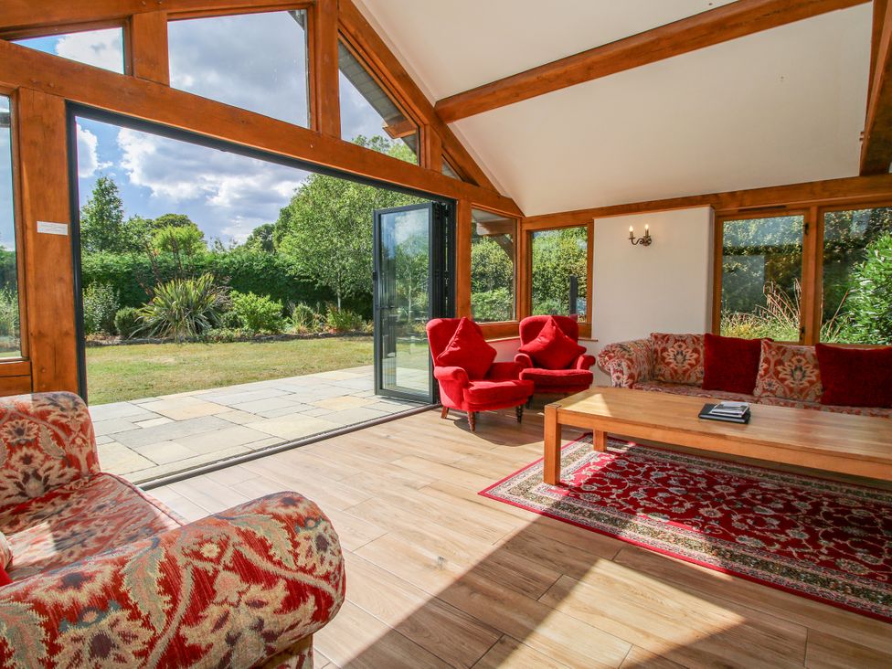 A sunroom with red chairs and a wooden table at The Old Farmhouse in Westhope