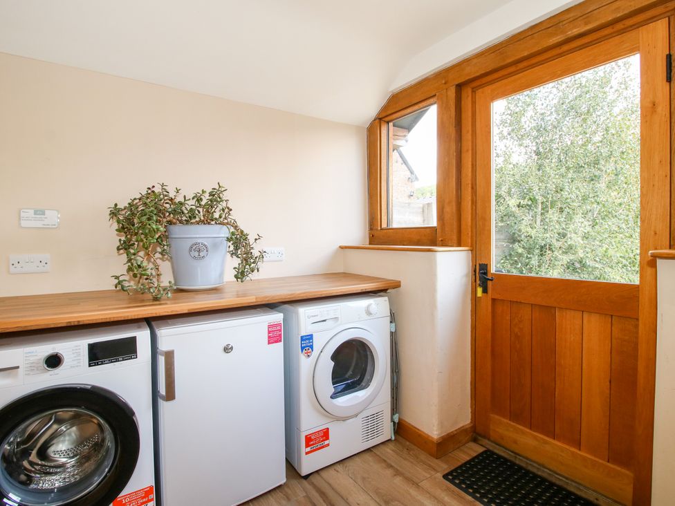 A laundry room with a washing machine and fridge at The Old Farmhouse in Westhope