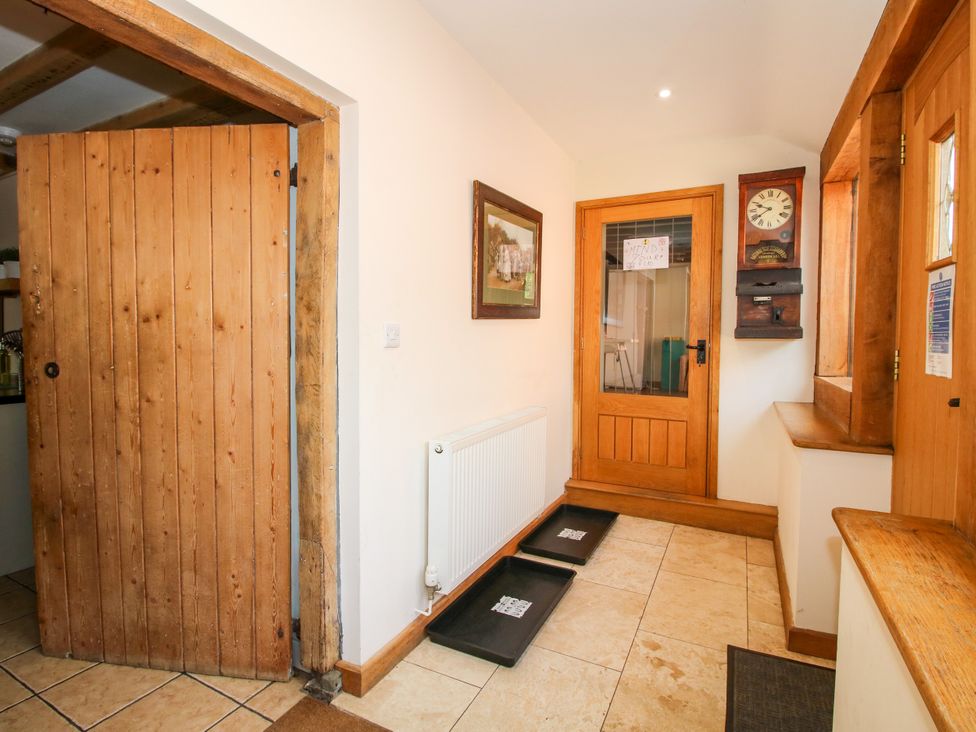A hallway with a wooden door and radiator at The Old Farmhouse in Westhope
