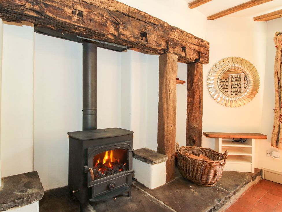 A living room with a stove and wooden beam at The Old Farmhouse in Westhope