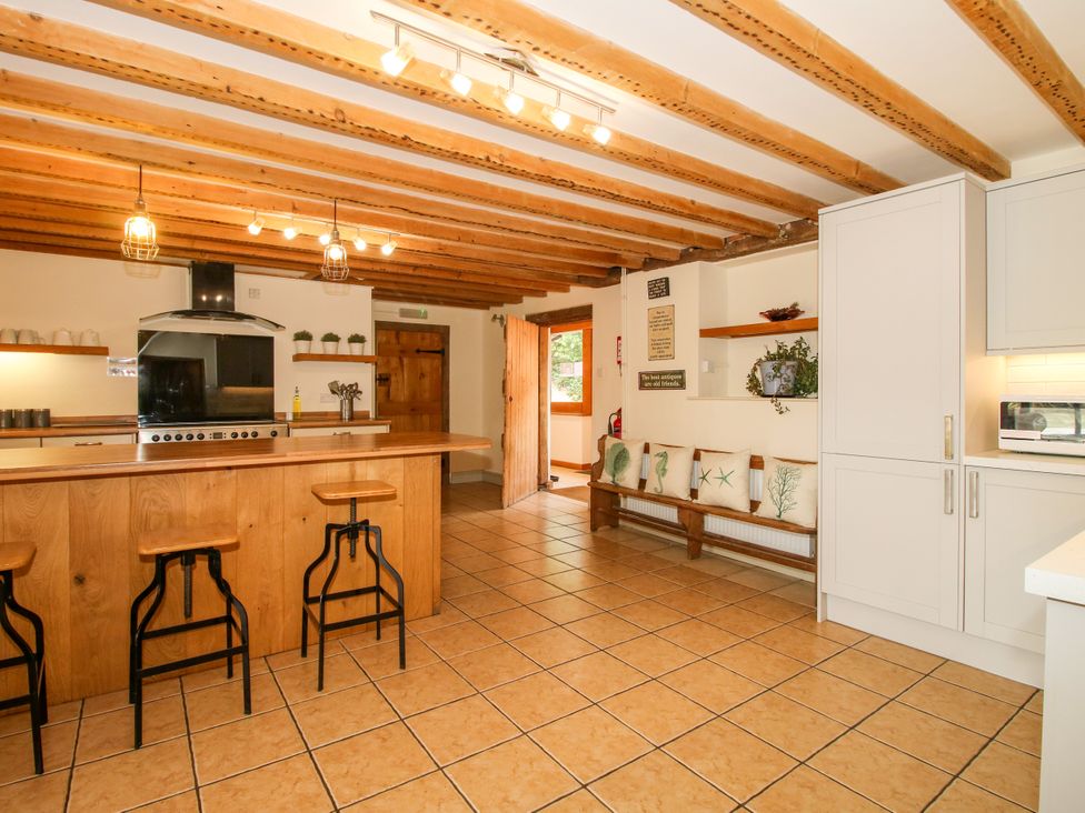 A kitchen with a wooden island and bar stools at The Old Farmhouse in Westhope