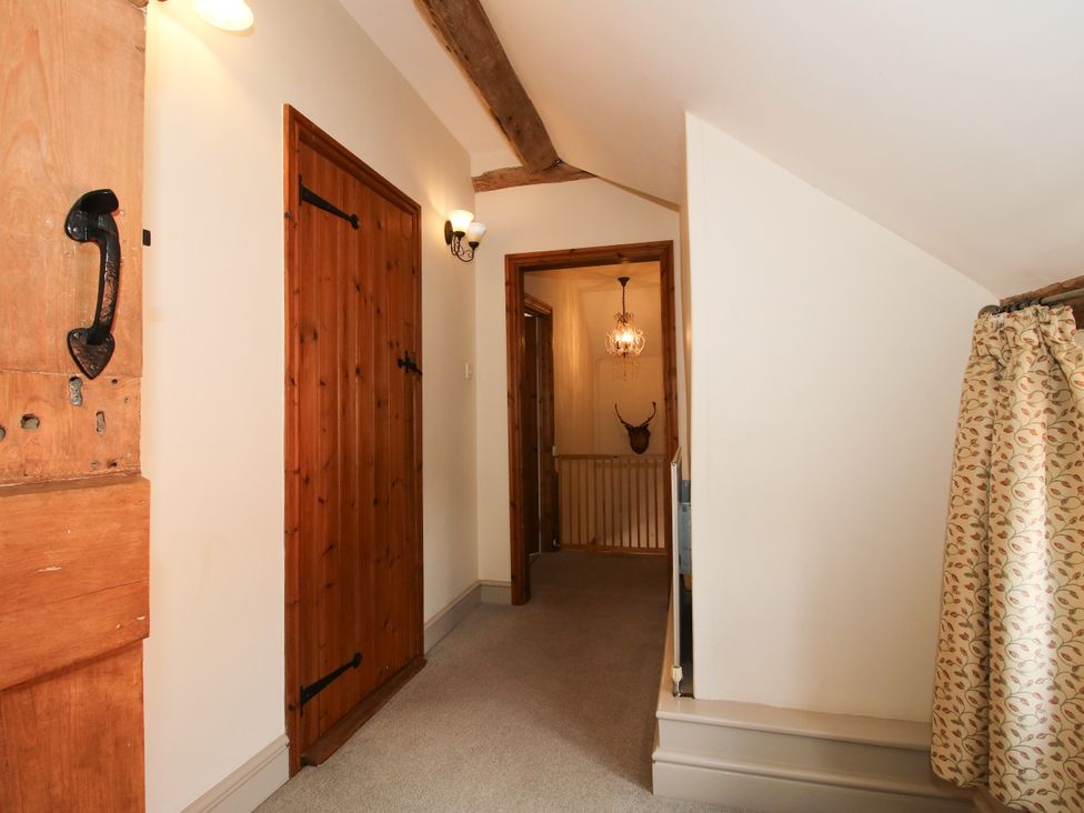A hallway with wooden doors and a staircase at The Old Farmhouse in Westhope