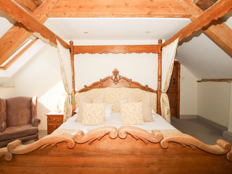 A bedroom with a four-poster bed and armchair at The Old Farmhouse in Westhope