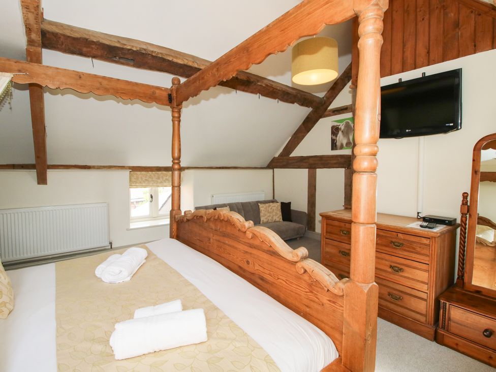 A bedroom with a four-poster bed and a dressing table at The Old Farmhouse in Westhope