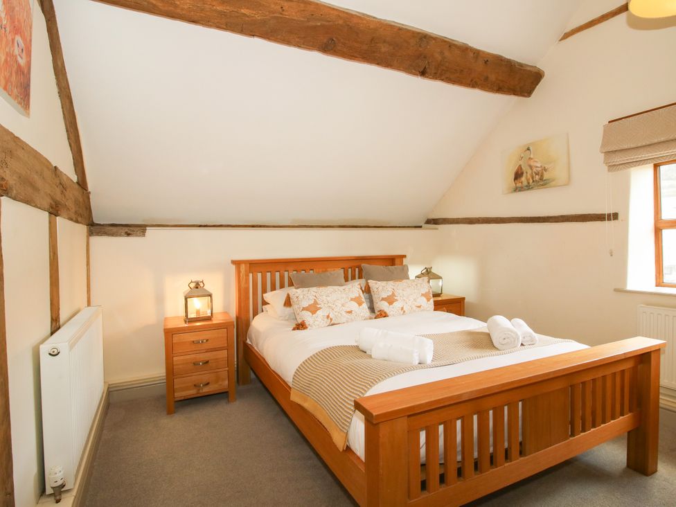 A bedroom with a wooden bed and nightstand at The Old Farmhouse in Westhope