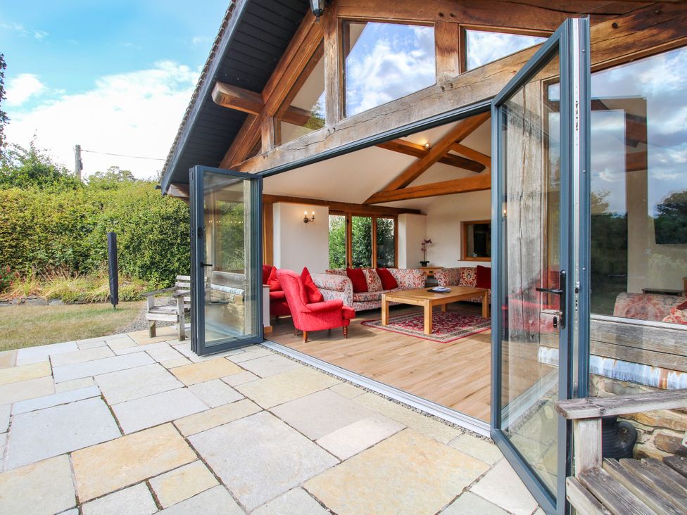 A living room with sliding doors and wooden furniture at The Old Farmhouse Westhope