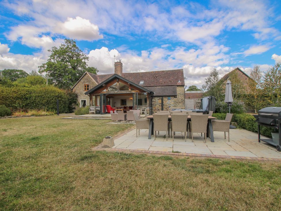 A garden with a house and patio dining area at The Old Farmhouse in Westhope