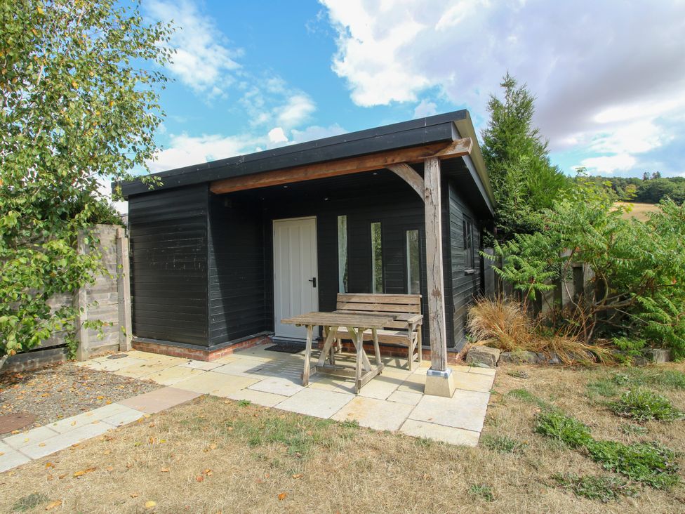 A garden shed with a table and chairs outside at The Old Farmhouse in Westhope