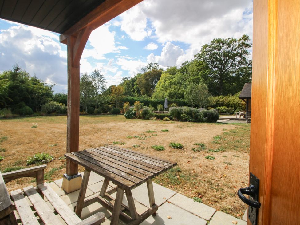 A patio area with a table and chairs overlooking a garden at The Old Farmhouse Westhope