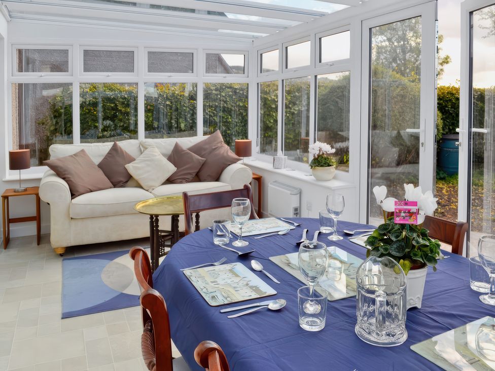 A conservatory with a dining table and a sofa at Sisial y Llyn in Bala