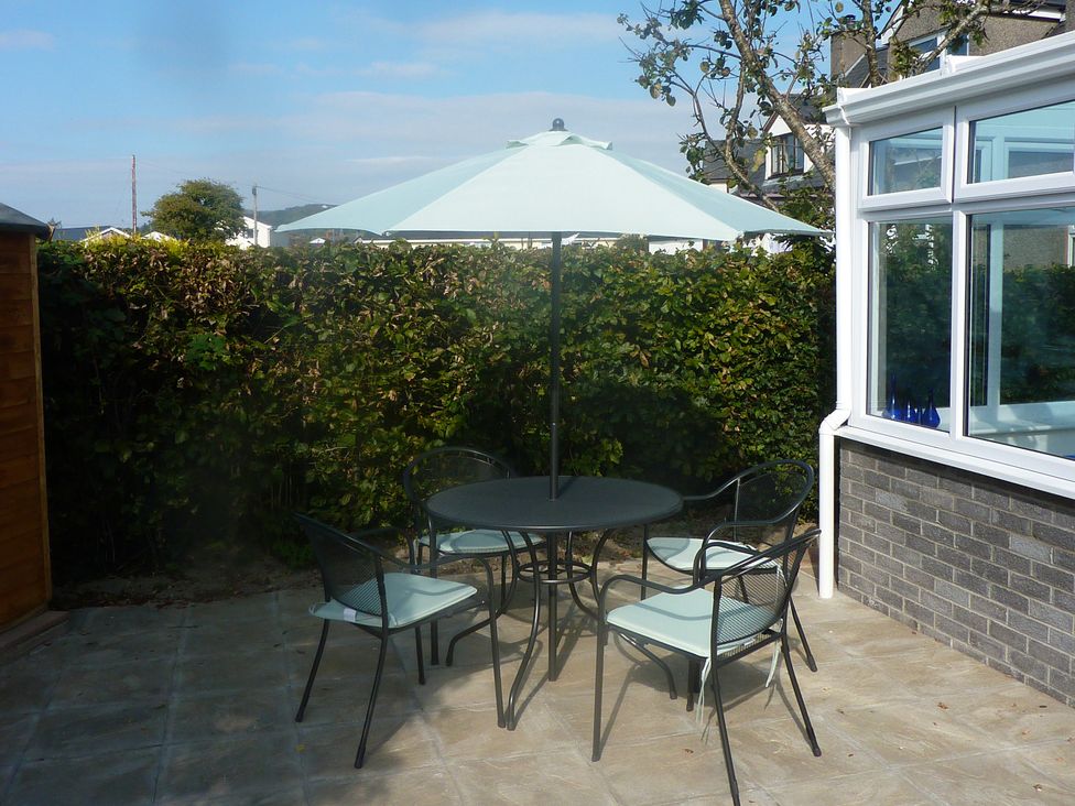 A patio with a table and chairs under an umbrella at Sisial y Llyn in Bala
