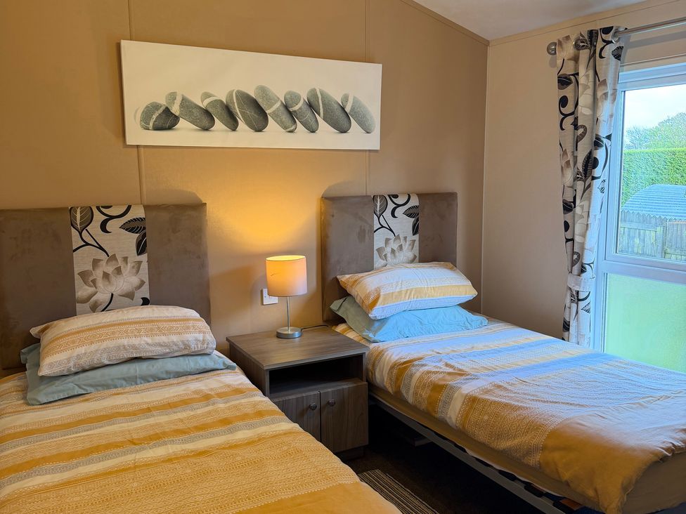 A bedroom with two beds and a nightstand at Cheri in Southerness