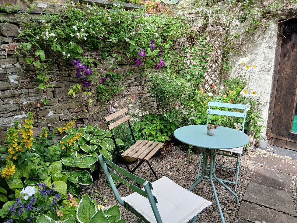 A garden with a table and chairs surrounded by plants at Arllen Fawr in Llanrhaeadr-ym-Mochnant
