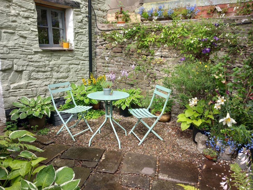 A garden with chairs and a table surrounded by plants at Arllen Fawr in Llanrhaeadr-ym-Mochnant
