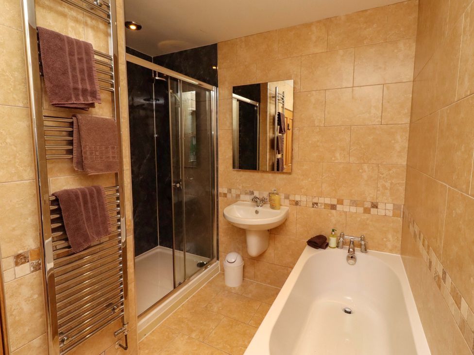 A bathroom with a bathtub, shower, sink, and towel rack at West Gate in Embleton