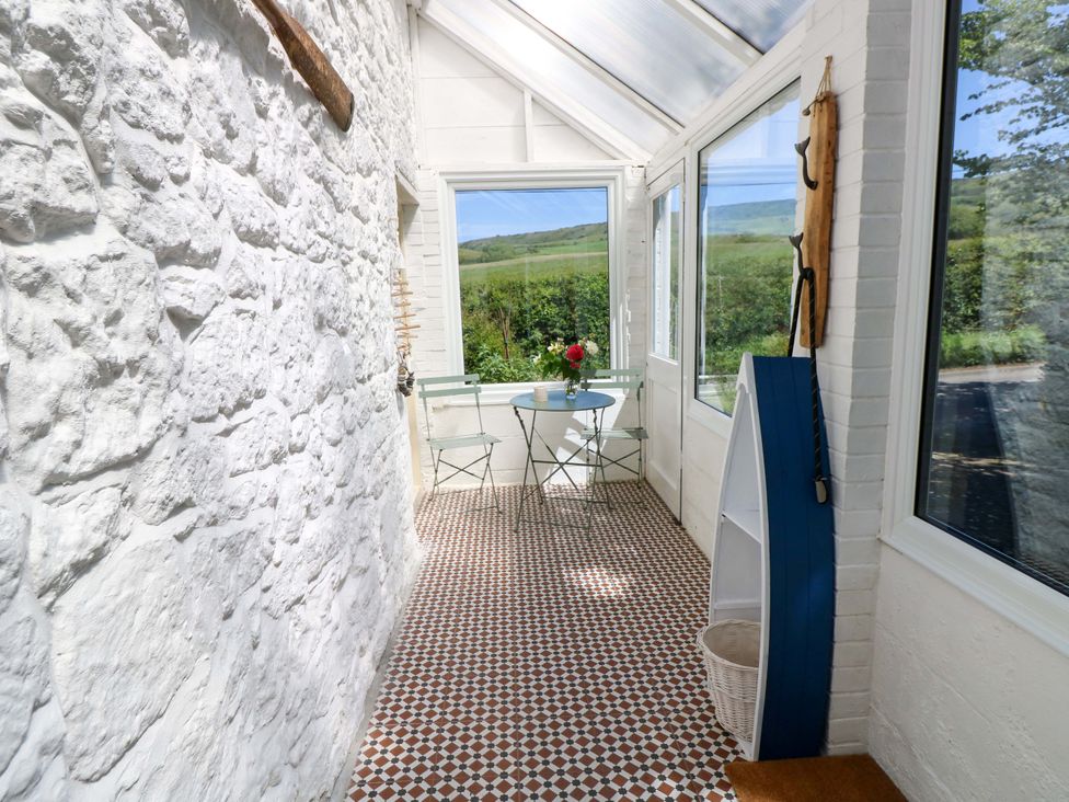 A conservatory with a small table and chairs at Sweet Briars in Chale