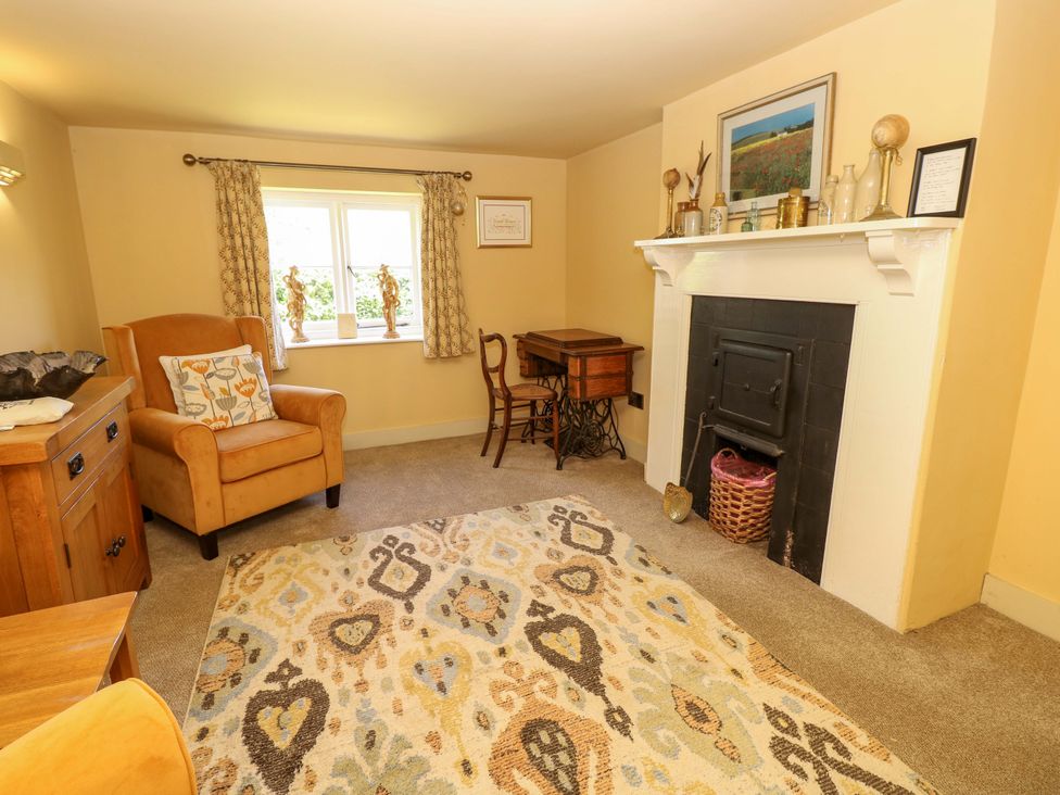 A living room with an armchair and a fireplace at Sweet Briars in Chale