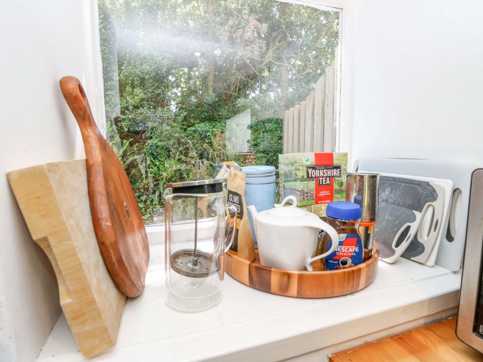A kitchen with tea and coffee items on a windowsill at Sweet Briars in Chale