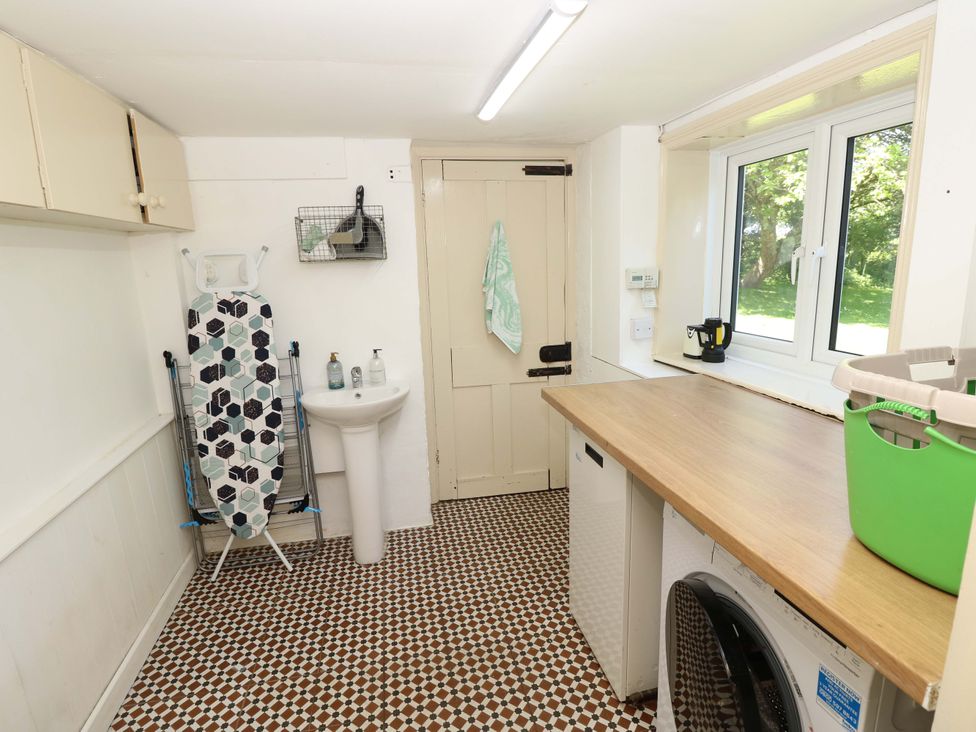 A laundry room with an ironing board and washing machine at Sweet Briars Chale