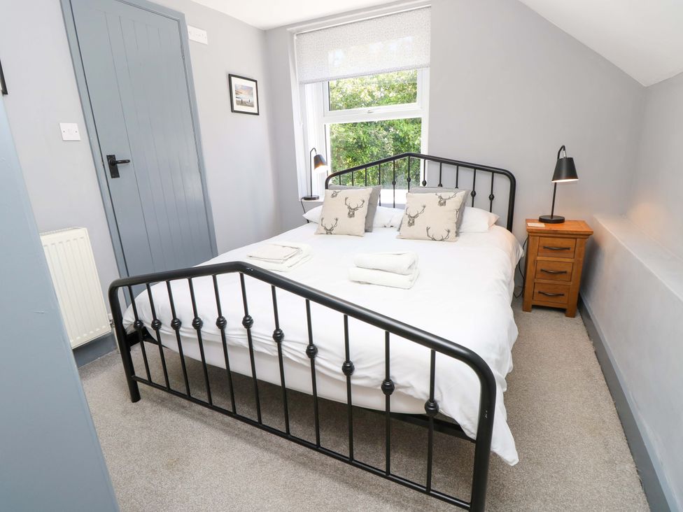 A bedroom with a bed and nightstand at Sweet Briars in Chale