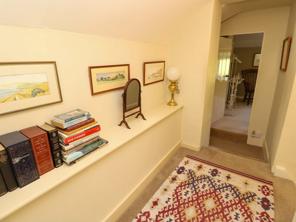 A hallway with books, a mirror, and a lamp at Sweet Briars in Chale