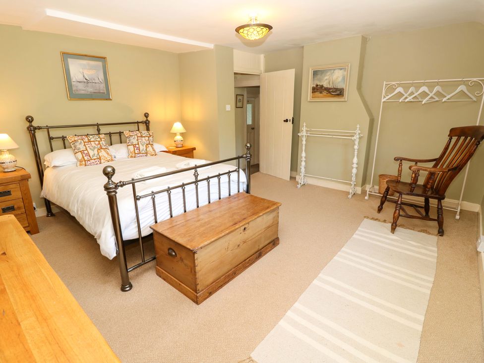 A bedroom with a bed, nightstand, lamp, and rocking chair at Sweet Briars in Chale