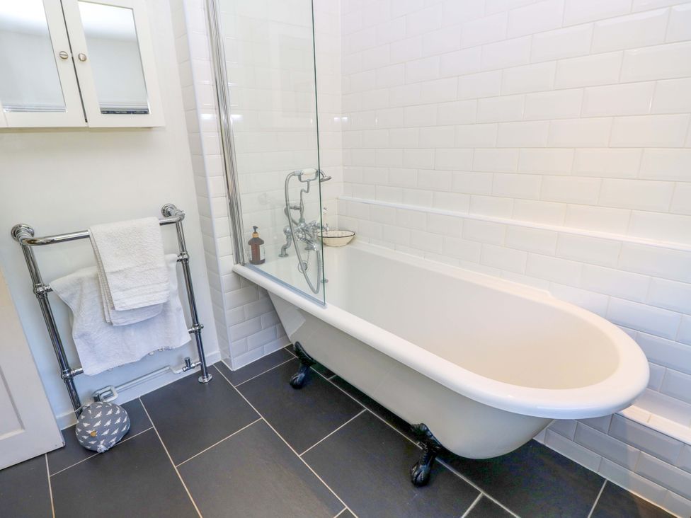 A bathroom with a bathtub and towel rail at Sweet Briars in Chale