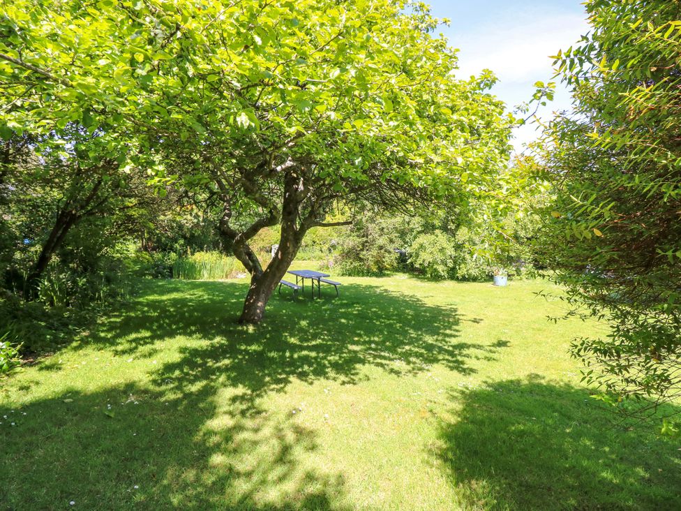 A garden with a table and trees at Sweet Briars in Chale