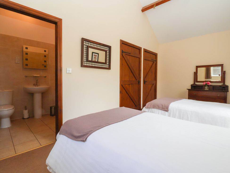 A bedroom with two beds and a bathroom entrance at Winsall Court I Gransmoor near Bridlington