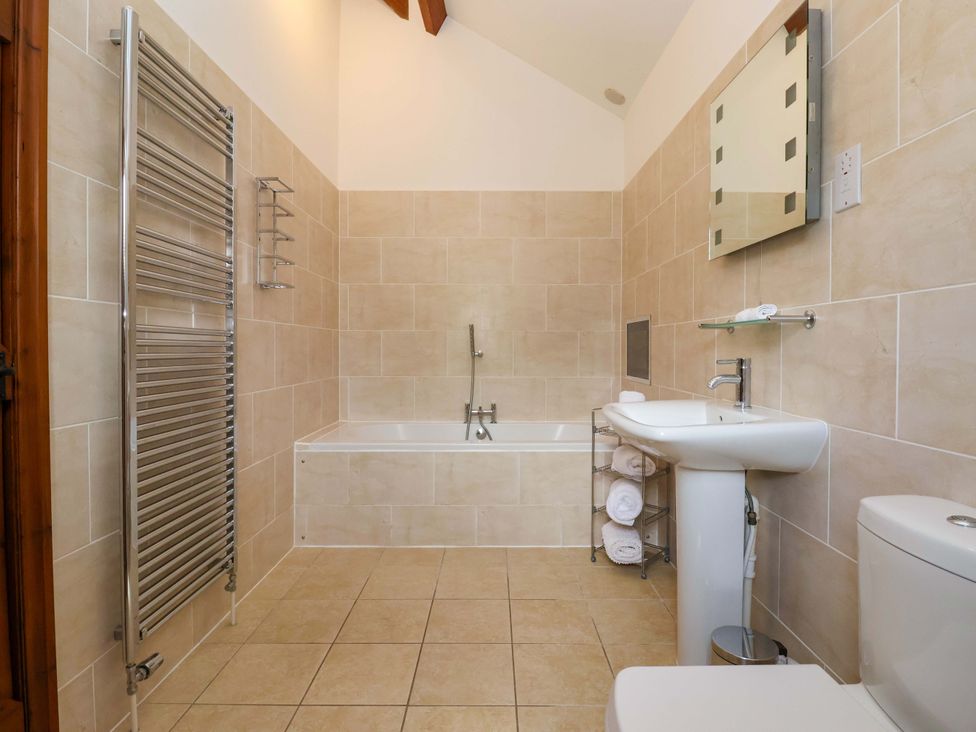 A bathroom with a bathtub, sink, and towel rack at Winsall Court II in Gransmoor near Bridlington