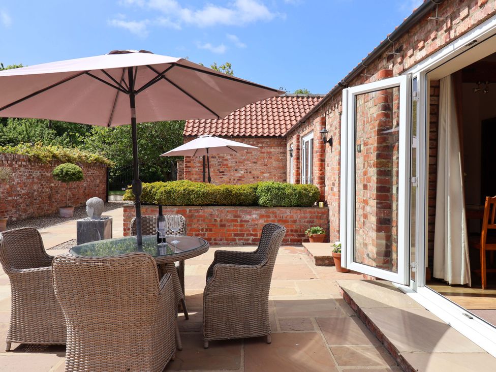 An outdoor area with a table and chairs under umbrellas at Winsall Court II in Gransmoor near Bridlington