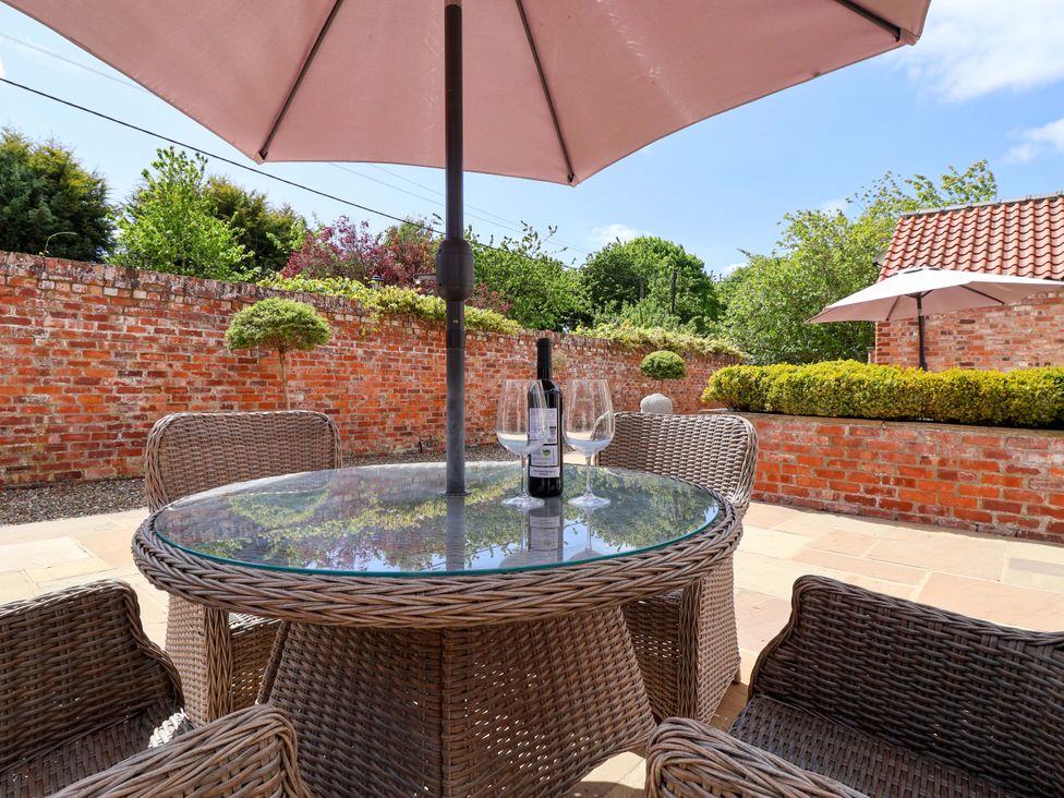 A table with a wine bottle and glasses in an outdoor seating area at Winsall Court II Gransmoor near Bridlington