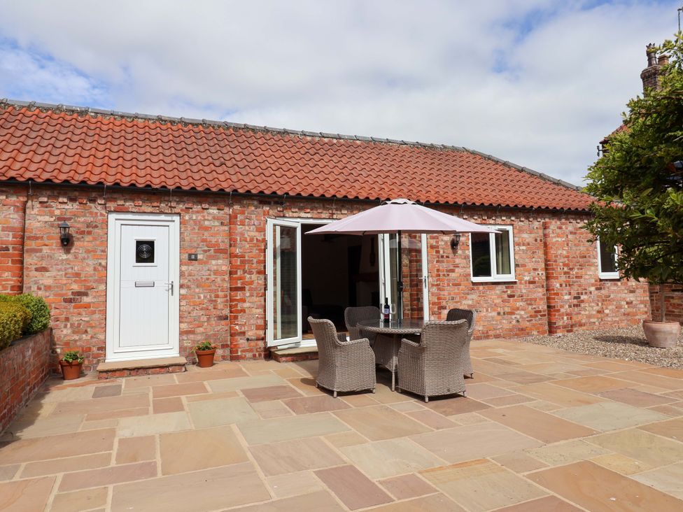 An outdoor area with a table and chairs under an umbrella at Winsall Court II Gransmoor near Bridlington