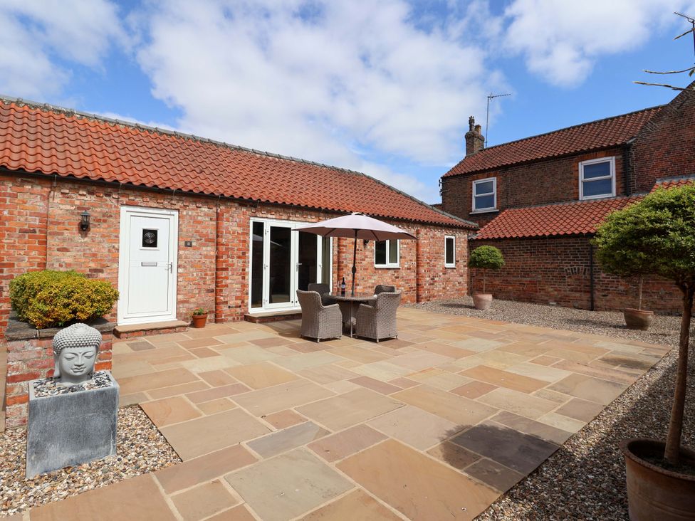 An outdoor seating area with an umbrella and flowerpots at Winsall Court II Gransmoor near Bridlington