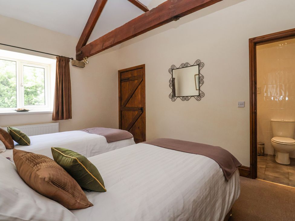 A bedroom with two beds and an ensuite bathroom at The Wagon Shed in Gransmoor near Bridlington