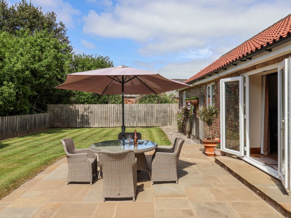 A garden with a table and chairs under an umbrella at The Wagon Shed Gransmoor near Bridlington