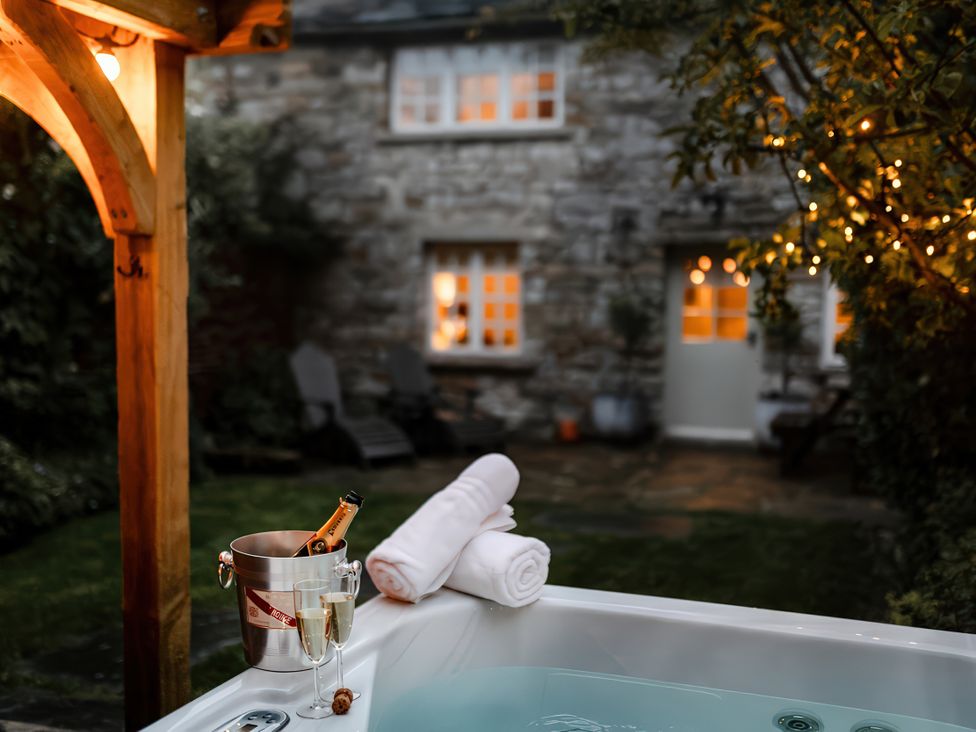 An outdoor hot tub with champagne glasses at Bridge End Cottage in Stainforth
