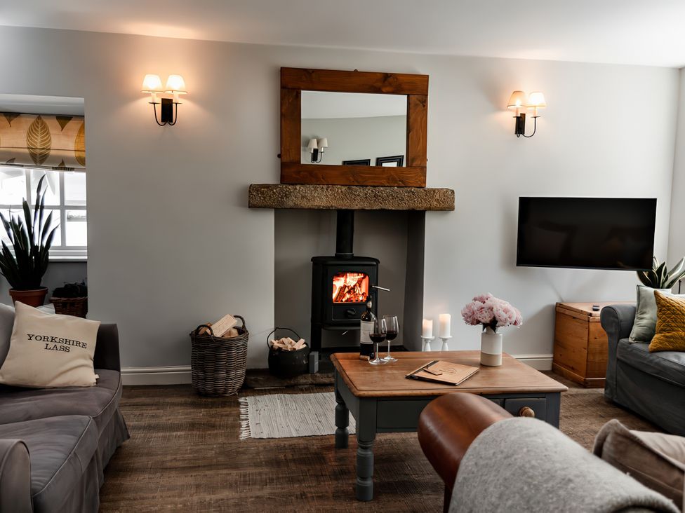 A living room with a fireplace and television at Bridge End Cottage in Stainforth