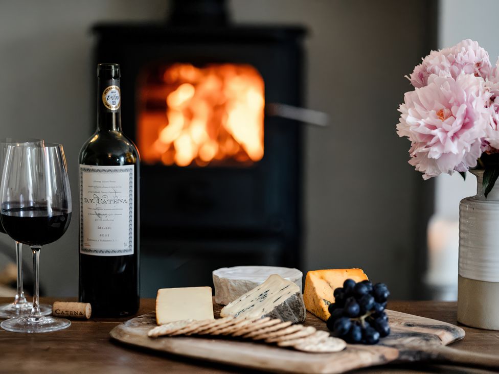 A table with wine and cheese in front of a fireplace at Bridge End Cottage Stainforth